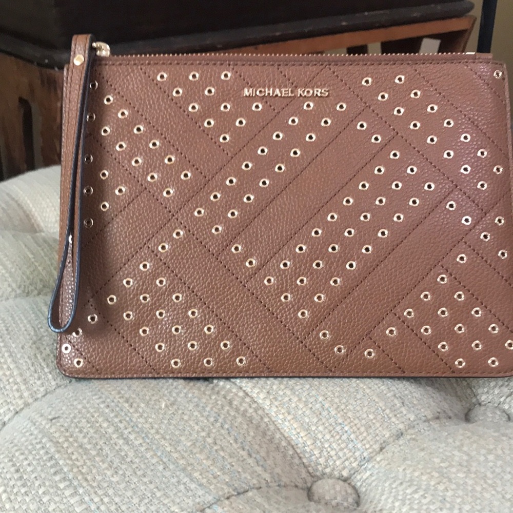 Michael Kors leather wristlet with gold rings adorning the front.